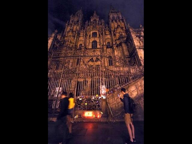 A tourist takes photographs of candles and flowers placed on the fence of the Cathedral in Plaza do Obradoiro in Santiago de Compostela, northern Spain, to remember victims of the high speed train crash on the eve of the Santiago de Compostela festivities. (AFP Photo)