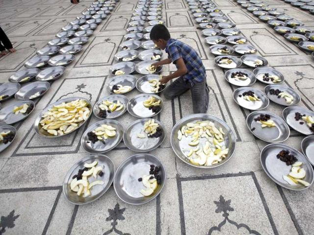 A volunteer prepares plates for Iftar during the holy month of Ramzan at a mosque in Karachi. (Reuters photo)
