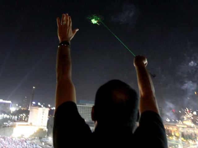 An anti-Mursi protester waves as a military helicopter passes over Tahrir square with lasers pointed at the helicopter during a mass protest to support the army in Tahrir square in Cairo, July 26, 2013. REUTERS