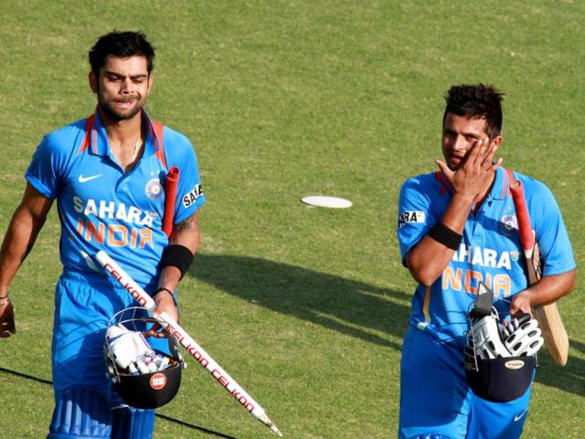 Indian batsmen Virati Kohli (L) and Suresh Raina walk off the pitch after beating Zimbabwe by seven wickets in their third ODI, in Harare. (AP Photo)