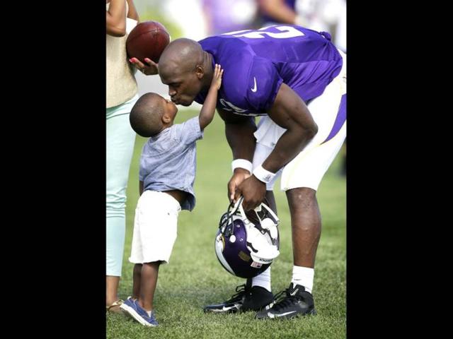 Minnesota Vikings running back Adrian Peterson gets a kiss from his son Adrian Jr at the end of practice at NFL football training camp in Mankato, Minn. (AP Photo)