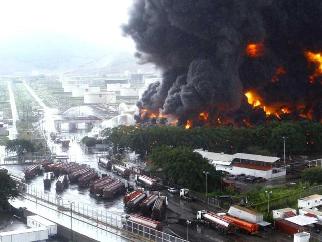 Firefighters try to extinguish a fire at an oil refinery in Puerto La Cruz. Lightning set fire to a storage tank at Venezuela's Puerto La Cruz oil refinery on Sunday, the president said, and residents were moved out of the immediate area while local media showed images of thick black smoke rising from the facility. REUTERS