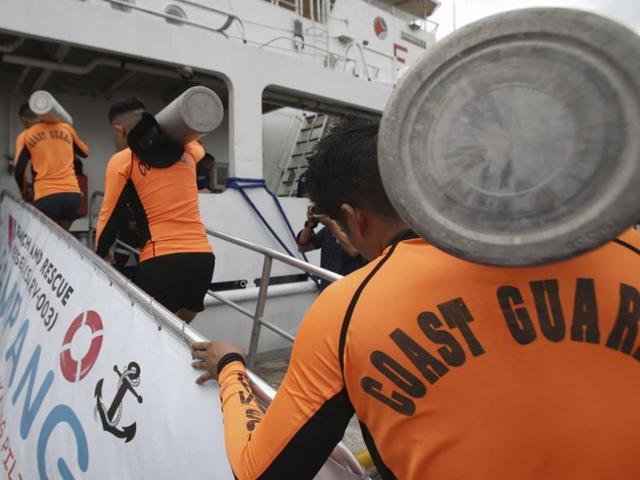 Coast guard divers carry oxygen tanks on board a ship at their headquarters in Manila, Philippines. Hundreds have been rescued but over 200 are still missing. (AP Photo)
