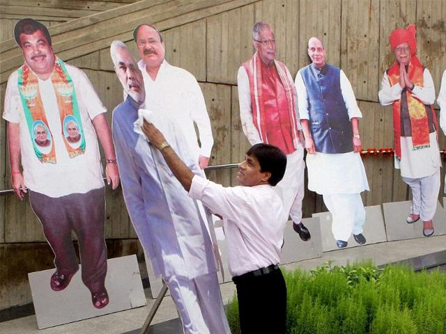 A worker cleans a Cut-out of Narendra Modi outside NDMC building where Party's National Election Campaign Committee meeting was held. (PTI).