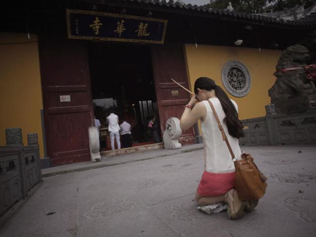 A woman offers prayers to her deceased relatives, burning joss sticks on the Ghost Festival at Longhua Temple in Shanghai, China. (AP Photo)