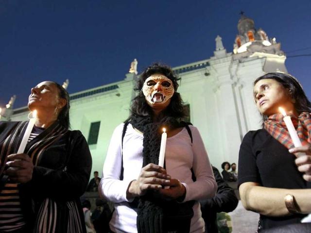 A woman wearing a mask in the likeness of a tigrillo, joins with others in a candlelight vigil, in protest against the government's decision to allow oil drilling in the Amazon reserve, Yasuni National Park, in Quito, Ecuador. (AP Photo)