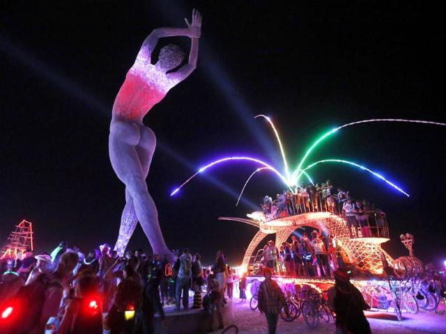 Participants dance around and atop an art car parked beside the "Truth is Beauty" sculpture created by Marco Cochrane. (Reuters Photo)