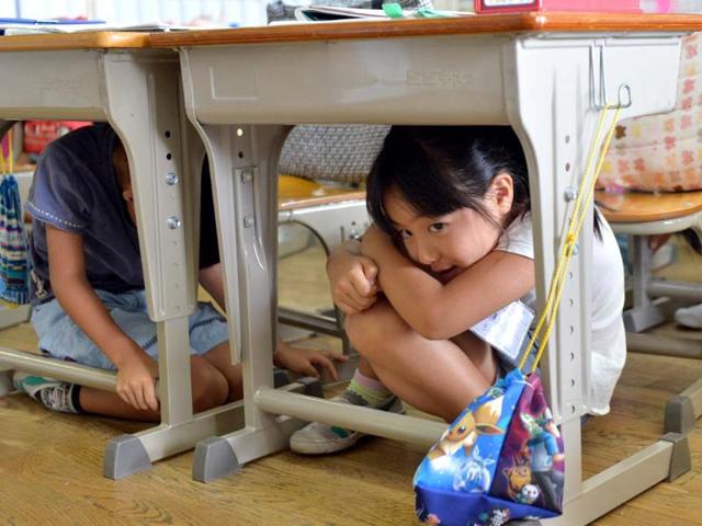 Elementary school children take cover under their desks during an earthquake drill at a school in Tokyo. (AFP Photo)