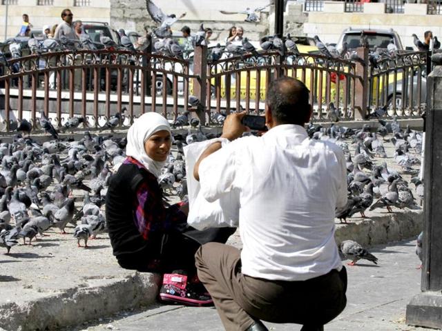 A Syrian girl poses for a photograph at a square in Damascus as residents come to relax from battles between regime forces and rebels. AFP photo