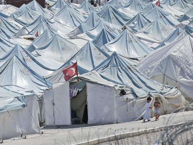 Children walk past tents of a Syrian refugees camp in Yayladagi, Turkey as the civil war in Syria has forced over 2 million people out of the country. AP photo