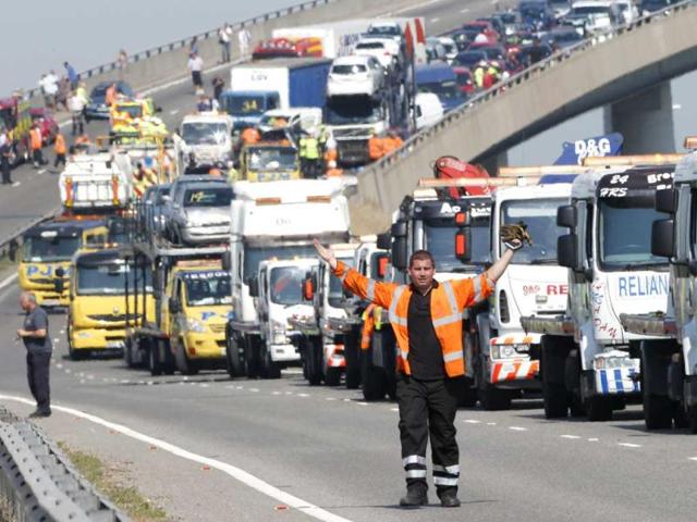 A rescue worker gestures in front of recovery trucks lined up to collect over 100 vehicles involved in multiple collisions on the Sheppey Bridge in Kent, east of London. (Reuters Photo)