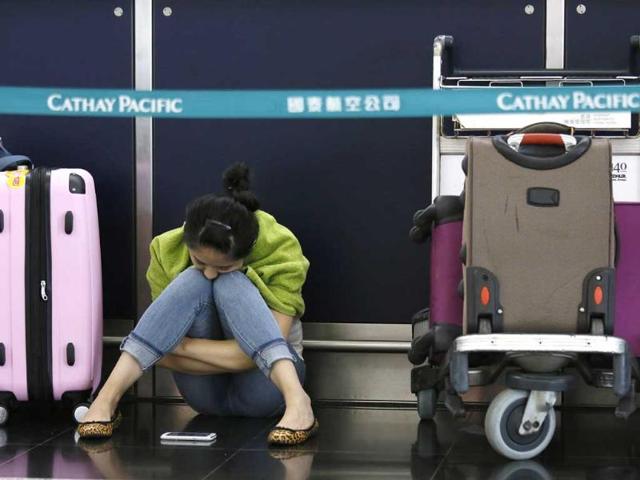 A passenger waits for flights to resume while sitting an airline counter at Hong Kong's international airport after Typhoon Usagi slammed into southern China. (AP Photo)