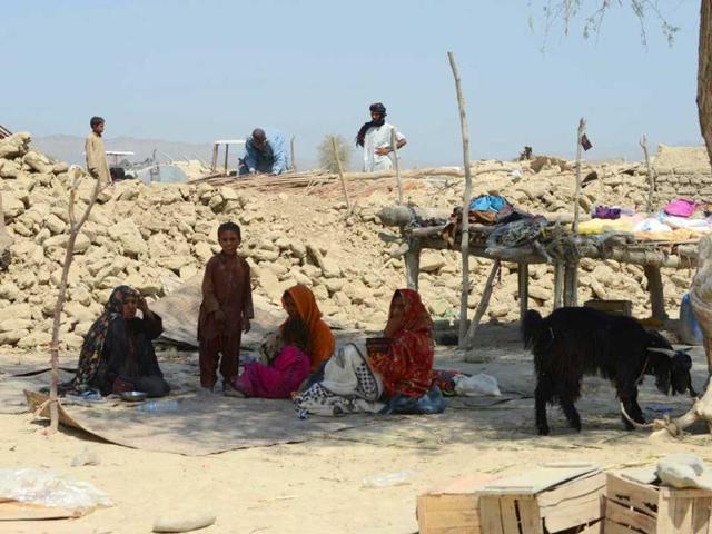 Pakistani earthquake survivors sit near their collapsed mud house in the earthquake-devastated district of Awaran. (AFP Photo)