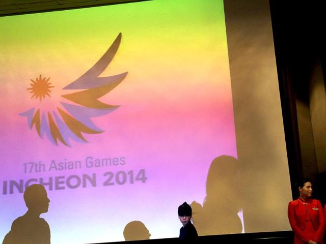 Shadows of hotel staff members and media personnel are cast against a giant screen showing the projection of the 17th Asian Games Incheon 2014 logo in Singapore. AP photo