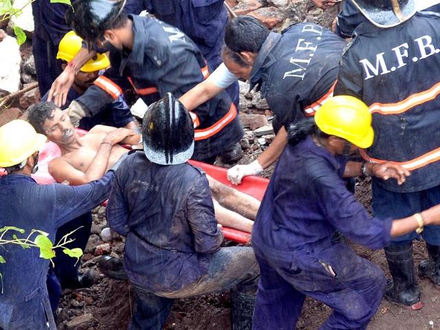 Firefighters and rescue workers bring out a survivor from under the rubble of a collapsed building in Mumbai (AFP Photo)
