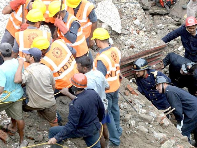 Firefighters (bottom right) look through a gap as they search for survivors at the site of the collapsed building in Mumbai. (AFP Photo)
