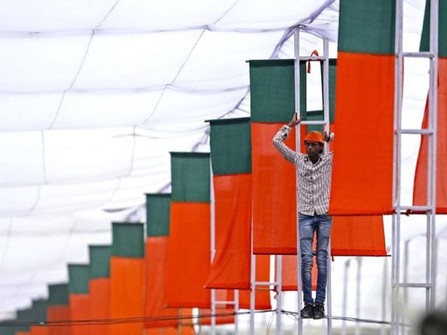 A supporter stands on a pole under a tent to watch Modi addressing his party supporters during a rally in New Delhi. (Reuters Photo)