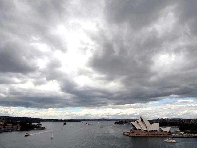 Dark clouds cover the sky over the iconic Sydney Opera House (centre) prior to the arrival of the tall ships on the eve of the International Fleet Review. (AFP Photo)