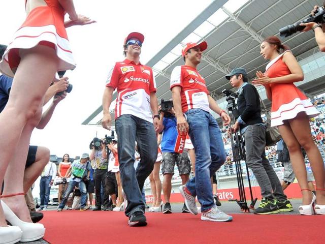 Ferrari driver Fernando Alonso of Spain (centre) and Ferrari driver Felipe Massa of Brazil (3rd right) walk past grid girls during a drivers track parade ahead of the start of the Formula One Korean Grand Prix in Yeongam. (AFP Photo)