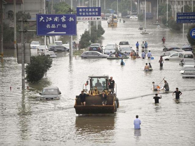 Residents travel on a bulldozer as others walk amid a flooded street after Typhoon Fitow hit Yuyao, Zhejiang province. (Reuters Photo)