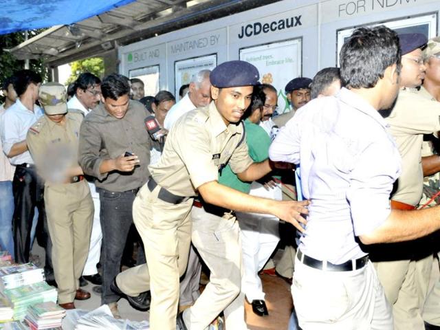 Policemen struggle to shield Moily as he leaves the Central Secretariat Metro station in New Delhi to walk to his office. (Mohd Zakir/HT)