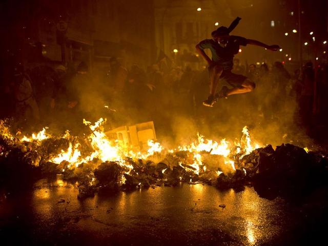 A demonstrator jumps over a burning barricade at the Cinelandia Square after violence erupted during a demonstration by teachers demanding higher pay, in Rio de Janeiro, Brazil. (AP Photo)