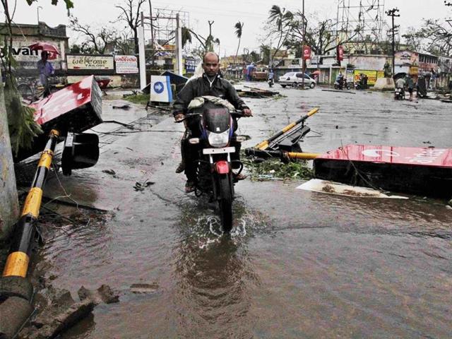 A motorcyclist rides past fallen traffic signal poles, post Cyclone Phailin in Berhampur. (PTI Photo)
