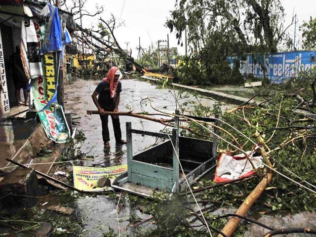 A man salvages a table stuck under uprooted trees, that fell during Cyclone Phailin, on a road in Berhampur. (AP Photo)