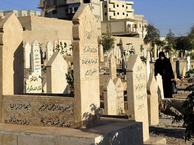 A woman prays near a grave as she visits a cemetery on the first day of Eid al-Adha in Syria. (Reuters photo)