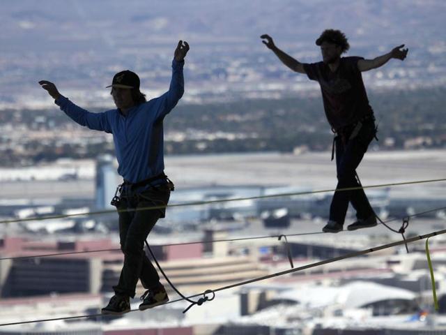 With McCarran Airport in the background, daredevil slackline athletes Mickey Wilson and Andy Lewis participate in a urban highline walk outside the 63rd floor of the Mandalay Bay in Las Vegas.(AP photo)