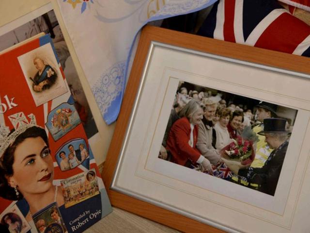 A framed photograph showing Britain's Queen Elizabeth receiving flowers from Margaret Tyler, who has dedicated her house as a shrine to the royal family. (Reuters Photo)