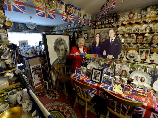 Margaret Tyler dusts some of the royal paraphernalia in the dining room of her home, which she has dedicated as a shrine to the British royal family. (Reuters Photo)