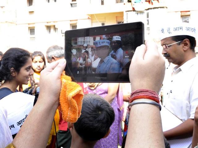 A woman takes a picture of Arvind Kejriwal while he interacts with residents of a multi-storey apartment in KG Marg in New Delhi. (HT Photo/ Sunil Saxena)