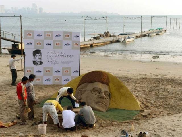 An Indian artist gives finishing touches to a sand sculpture of the late Bollywood playback singer Manna Dey on the beach in Mumbai on October 24, 2013. (AFP Photo)