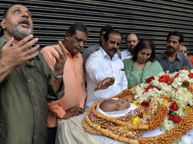 An emotional fan sings a song by late Bollywood playback singer Manna Dey, his mortal remains seen at right, as mourners pay their last respects to the artist who passed away following multiple organ failure aged 94 in Bangalore on October 24, 2013. (AFP Photo)