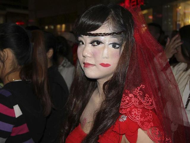 A woman who drew part of a face on her cheek, stands among the crowd at a costume party to celebrate Halloween in Wuhan, Hubei province. REUTERS