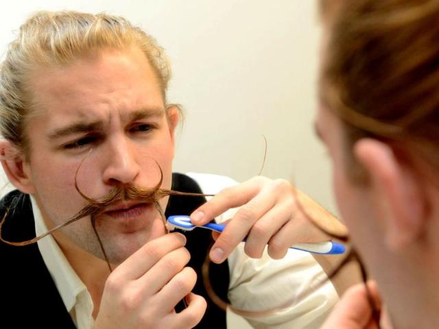 Felix Hammoser uses a toothbrush to style his beard as he prepares for the Beard World Championships. (AFP Photo)