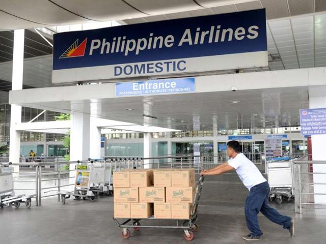 A delivery man passes a Philippine Airlines sign at the domestic flights entrance of Manila's International airport on November 8, 2013. One of the most intense typhoons ever recorded tore into the Philippines on November 8, triggering flash floods and ripping down buildings as millions of people huddled indoors. (AFP photo)