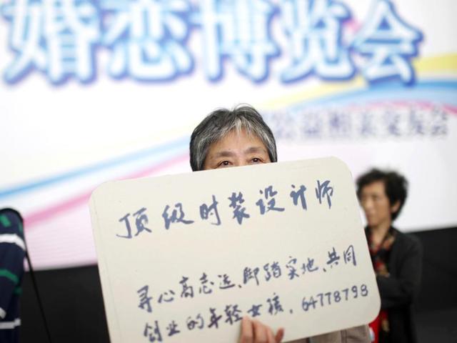 A woman holds the information card of her bachelor family member during a mass match-making event ahead of Singles Day in Shanghai, China. (AP Photo)