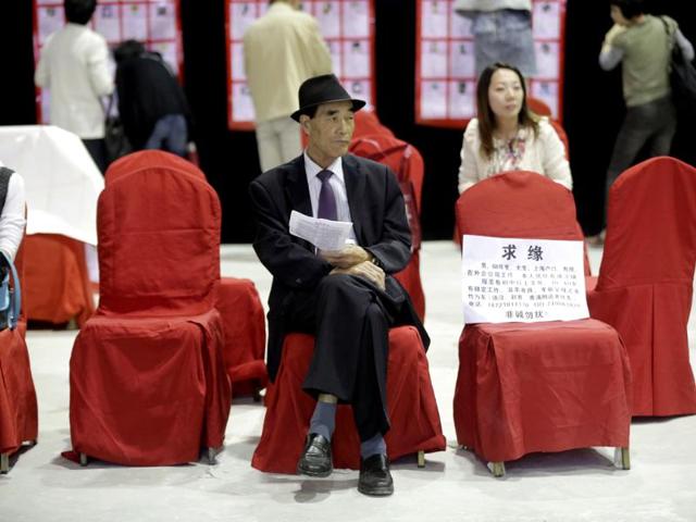 A man sits with the information card of his bachelor family member during a mass match-making event ahead of Singles Day in Shanghai, China. (AP Photo)