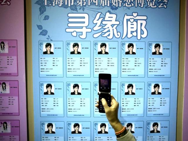 A participant takes a photo of the information cards of bachelors on the wall during a mass match-making event ahead of Singles Day in Shanghai, China. (AP Photo)