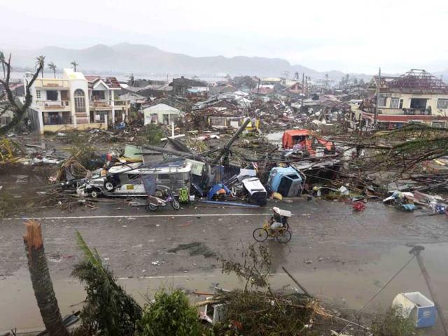 A man pedals his bike beside the devastation in Tacloban city, Leyte province, central Philippines on Sunday. (AP PHOTO)