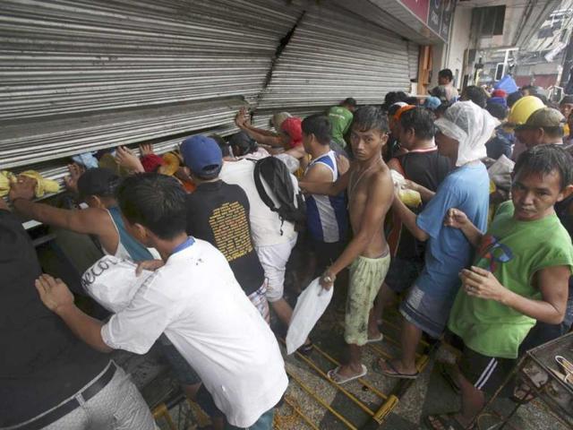 Residents push a shutter to open a small grocery to get food in Tacloban city, Leyte province central Philippines on Sunday. (AFP PHOTO)