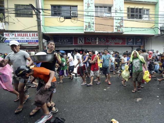 Residents run out carrying food after storming a grocery shop in Tacloban city, Leyte province central Philippines on Sunday.(AP PHOTO)