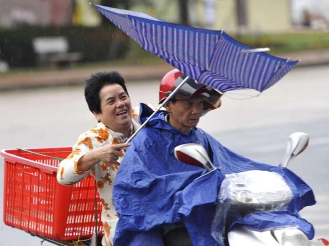 People ride against rain and wind under the influence of Typhoon Haiyan, in Qionghai, south China's Hainan province on sunday.(REUTERS PHOTO)