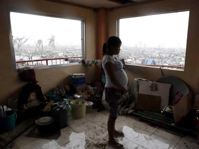 A pregnant woman cooks a meal inside a building overlooking destroyed houses after Super Typhoon Haiyan battered Tacloban city in central Philippines on Sunday.(REUTERS PHOTO)