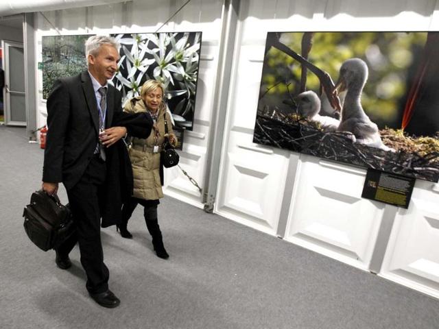 Delegates walk in front of pictures, part of exhibition "Arbores Vitae", the last European primeval forest, before the opening of the conference. (Reuters Photo)