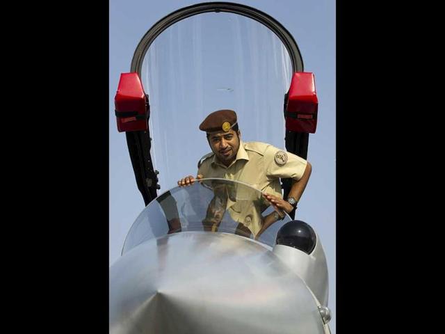 A member of the United Arab Emirates army gets into a model of a fighter jet during the Dubai Airshow. (Reuters Photo)