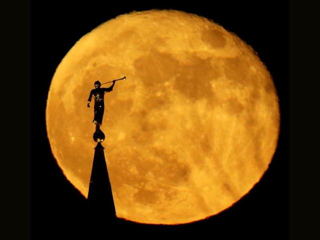 A statue of the Angel Moroni on top of a Latter-day Saints temple is silhouetted against the rising full moon in Kansas City. (AP Photo)
