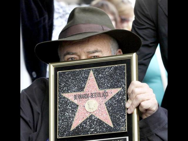 Italian director Bernardo Bertolucci holds a star plaque as he makes a rare visit to his star on the Hollywood Walk of Fame in Los Angeles. (AP Photo)